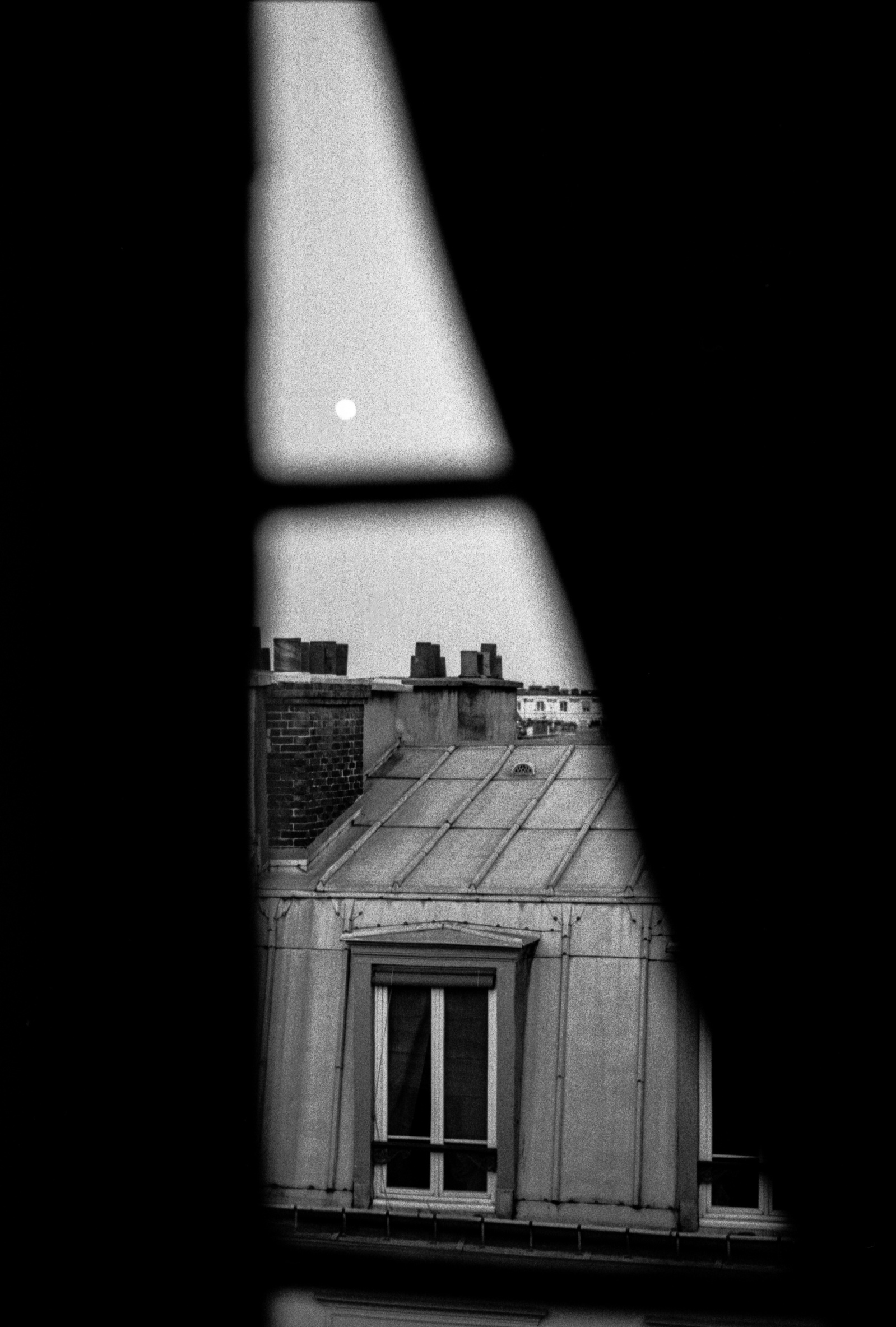 The moon rises above Parisian rooftops. Paris, March 2016. Photographed by Matthew Fleming on 35mm Ilford HP5 film with a Leica M6.