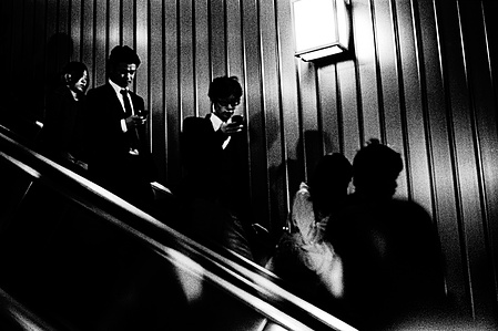 Commuters travel down an escalator into the Tokyo Underground Subway.
From the photographic series "In Praise of Shadows". Shot on black and white film by photographer Matthew Fleming. 