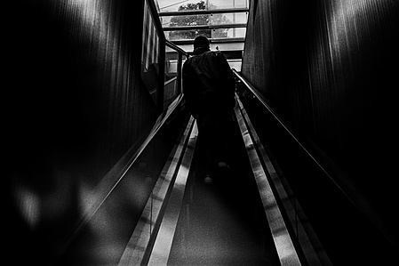 A figure emerges into the light from the Tokyo Underground. 
From the photographic series "In Praise of Shadows". Shot on black and white film by photographer Matthew Fleming. 
