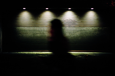 A silhouetted figure passes a closed shop at night. Kyoto. 
Photograph from the series Forbidden Colours by Matthew James Fleming. Taken with a Leica M6 and Kodak Portra 800.