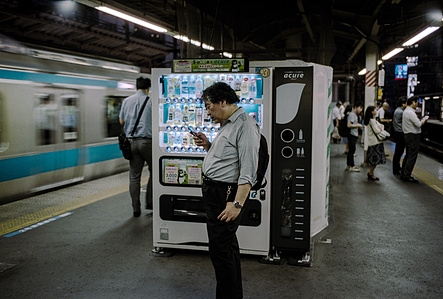 A man checks his phone by a train station vending machine, Tokyo. 
Photograph from the series Forbidden Colours by Matthew James Fleming. Taken with a Leica M6 and Kodak Portra 400 35mm film.