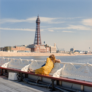 A woman gazed out on Blackpool front, with Blackpool tower looming large in the background, whilst seated on the traditional North Pier. Photograph taken by Matthew Fleming with a Hasselblad 500Cm and Kodak Portra 400 