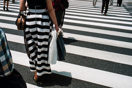 A woman in a striped skirt crosses one of Ginza's famous pedestrian crossings, Tokyo. 
Photograph from the series Forbidden Colours by Matthew James Fleming. Taken with a Leica M6 and Kodak Portra 800.