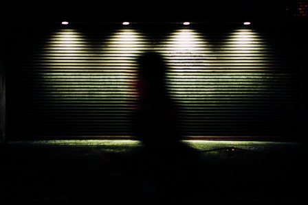 A silhouetted figure passes a closed shop at night. Kyoto. 
Photograph from the series Forbidden Colours by Matthew James Fleming. Taken with a Leica M6 and Kodak Portra 800.