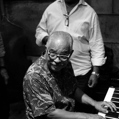 Black and white street photography of the french street photographer David Décamps representing a man playing piano in a jazz club in New Orleans, USA.