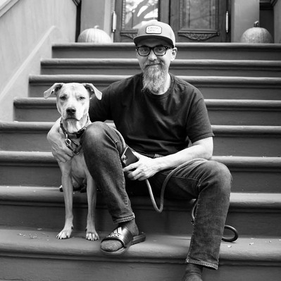 Black and white street photography of the french street photographer David Décamps representing a man with his dog on her stairs in New York City.