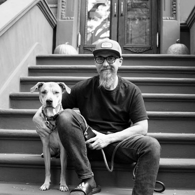 Black and white street photography of the french street photographer David Décamps representing a man with his dog on her stairs in New York City.
