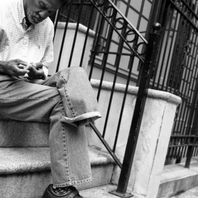 Black and white street photography of the french street photographer David Décamps representing a man with one leg sit in his stairs in New York City, USA.