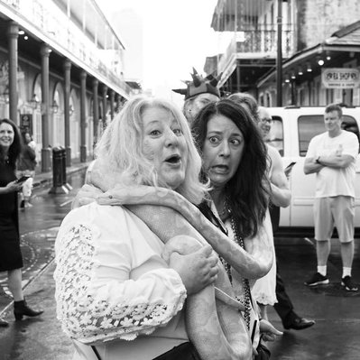 Black and white street photography of the french street photographer David Décamps representing two women screaming with a snake around their neck in New Orleans, USA.
