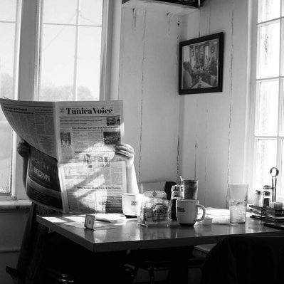 Black and white street photography of the french street photographer David Décamps representing a woman reading the newspaper in Tunica, USA.