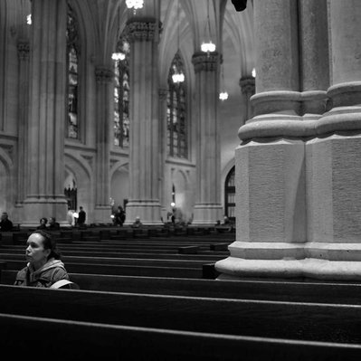 Black and white street photography of the french street photographer David Décamps representing a woman in a church in New York City, USA.