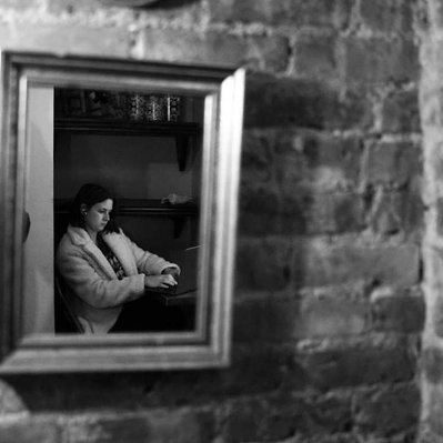 Black and white street photography of the french street photographer David Décamps representing a woman in a mirror in a bar in New York City, USA.