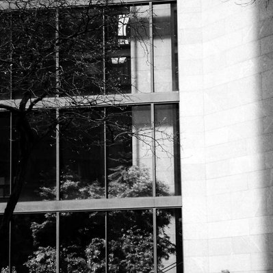 Black and white street photography of the french street photographer David Décamps representing an old man standing in front of a building in New York City, USA.