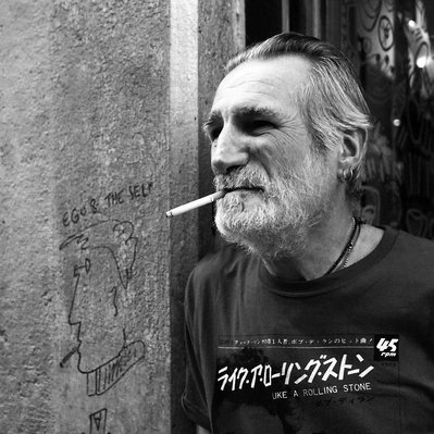 Black and white street photography of the french street photographer David Décamps representing a man with a cigarette and a pain similar as the man in Lyon.