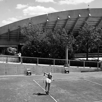 Black and white street photography of the french street photographer David Décamps representing a woman tennis player serving during Roland Garros in Paris.