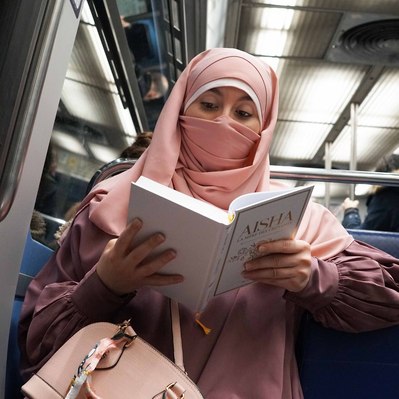 Street photography in colors of  the french street photographer David Décamps representing a woman dressed in pink reading a book in the subway in Paris.