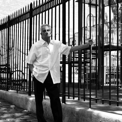 Black and white street photography of the french street photographer David Décamps representing an old man holding a fence  in New York City, USA.