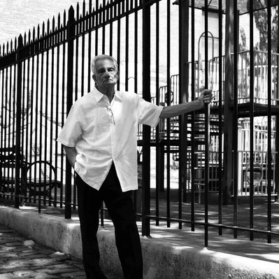 Black and white street photography of the french street photographer David Décamps representing an old man holding a fence  in New York City, USA.