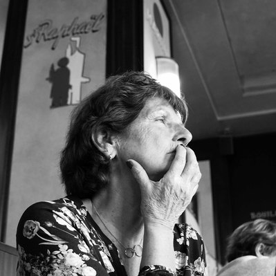 Black and white street photography of the french street photographer David Décamps representing a woman thinking alone in a restaurant in Paris.