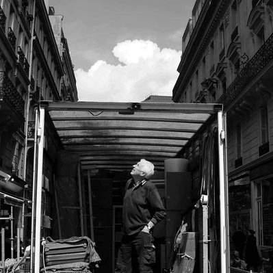 Black and white street photography of the french street photographer David Décamps representing a man in the back of his truck in Paris.