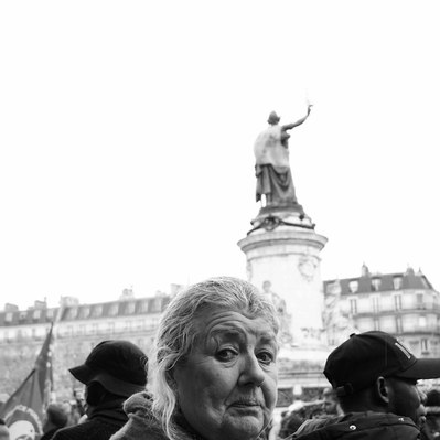 Black and white street photography of the french street photographer David Décamps representing the portrait of an woman with a statue in her back in Paris.