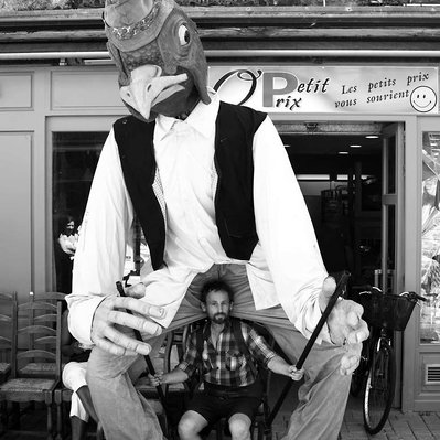 Black and white street photography of the french street photographer David Décamps representing a man under the costume of a giant puppet.