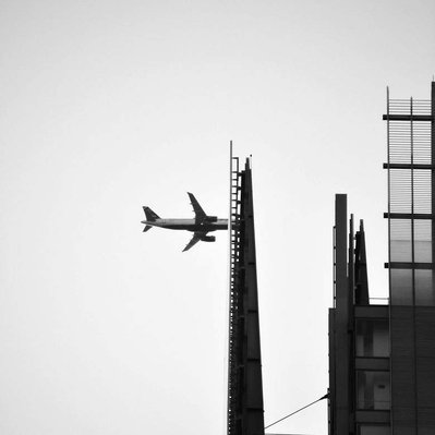 Black and white street photography of the french street photographer David Décamps representing a fake crash of an airplane in a building in New York City, USA.