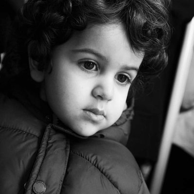 Black and white street photography of the french street photographer David Décamps representing a portrait of a baby boy with curly hair in Paris.
