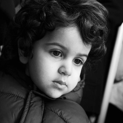 Black and white street photography of the french street photographer David Décamps representing a portrait of a baby boy with curly hair in Paris.
