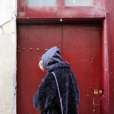 Street photography in colors of the french street photographer David Décamps representing a woman dressed up in violet in front of a red door in Paris.