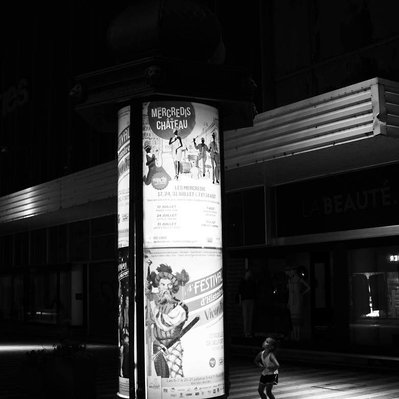 Black and white street photography of the french street photographer David Décamps representing a little girl amazed in front a giant advertising in Belfort.