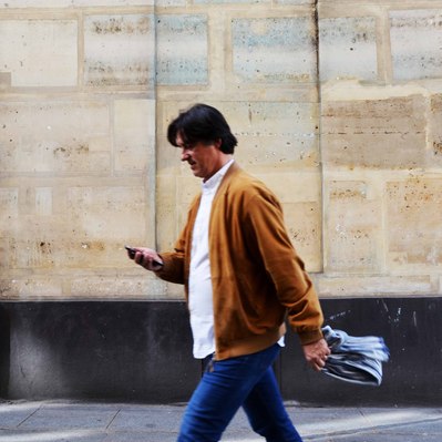 Street photography in colors of the french street photographer David Décamps representing a man walking with a scarf in his hand in Paris.