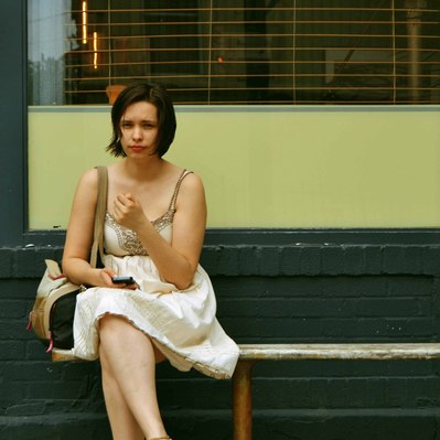 Street photography in colors of the french street photographer David Décamps representing a woman with a dress on a bench in New York City, USA.
