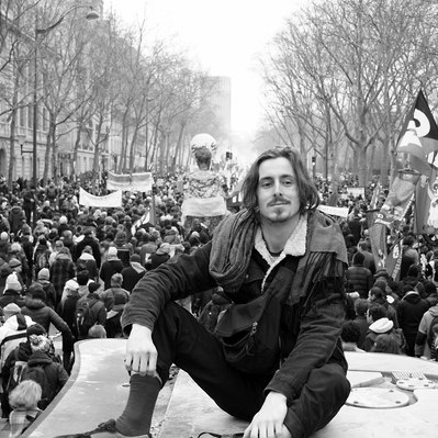Black and white street photography of the french street photographer David Décamps representing a young man sit on a bus station during the strike in Paris.