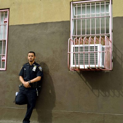 Street photography in colors of  the french street photographer David Décamps representing a police man leaned on a yellow wall in New York City, USA.