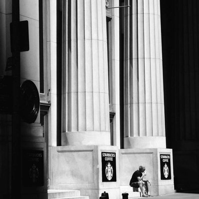 Black and white street photography of the french street photographer David Décamps representing a man drinking his Starbucks Coffee in New York City, USA.