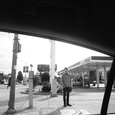 Black and white street photography of the french street photographer David Décamps representing a man smiling on the sidewalk in Los Angeles, USA.
