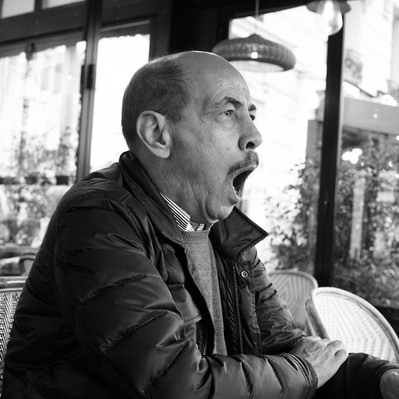 Black and white street photography of the french street photographer David Décamps representing a man yawning in a bar in Paris.