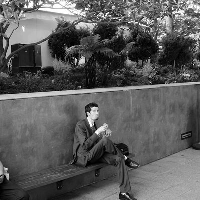 Black and white street photography of the french street photographer David Décamps representing a man eating the full mouth in Paris.