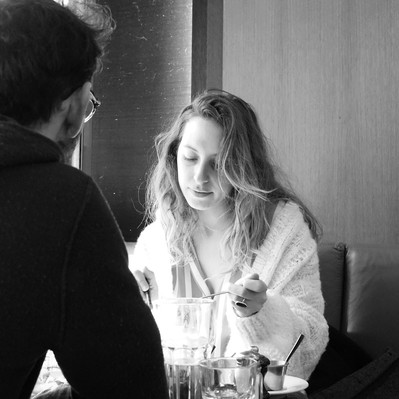 Black and white street photography of the french street photographer David Décamps representing a woman eating in a bar in Paris.