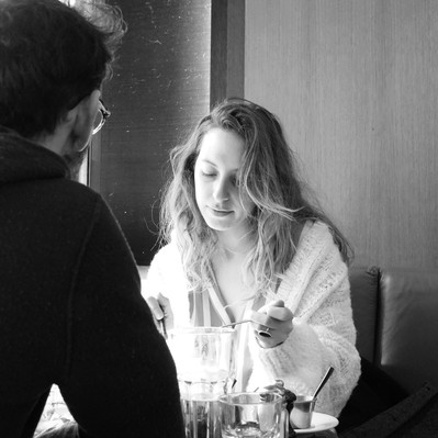 Black and white street photography of the french street photographer David Décamps representing a woman eating in a bar in Paris.