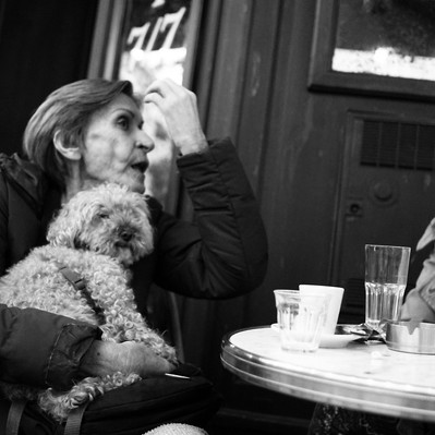 Black and white street photography of the french street photographer David Décamps representing a woman on a terasse with her dog in Paris.