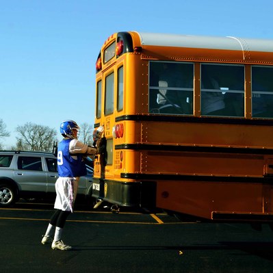 Street photography in colors of the french street photographer David Décamps representing a football player closing the door of a school bus in New York City, USA.