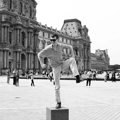 Black and white street photography of the french street photographer David Décamps representing a young man standing on one leg in Paris.