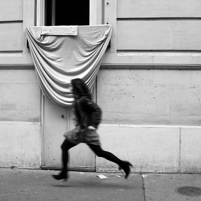 Black and white street photography of the french street photographer David Décamps representing a woman floating while running.