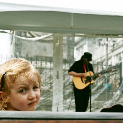 Street photography in colors of the french street photographer David Décamps representing a blond baby girl listening music on a bench in Montréal.