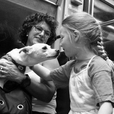 Black and white street photography of the french street photographer David Décamps representing a kid kissing a dog in the subway in Paris.