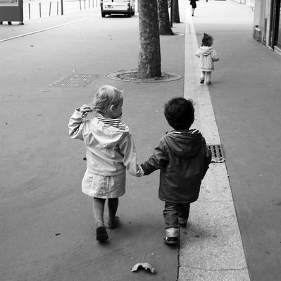Black and white street photography of the french street photographer David Décamps representing a baby couple walking side by side in Paris.