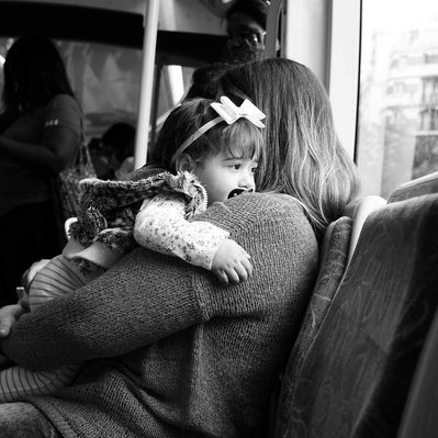 Black and white street photography of the french street photographer David Décamps representing a baby girl in her mother's arms in the tramway in Paris.