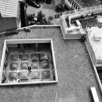 Black and white street photography of  the french street photographer David Décamps representing a man sleeping on a roof in Paris.